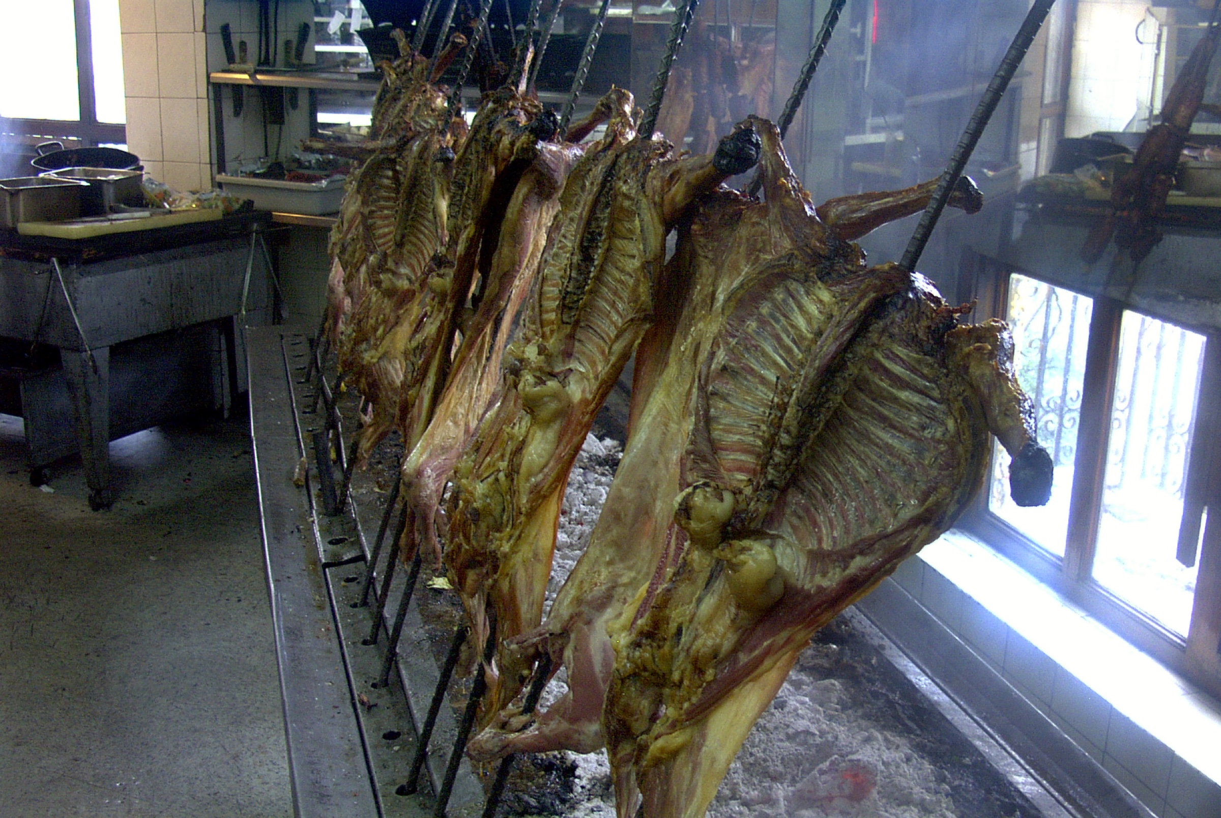 Cabritos roasting on vertical spits over coals